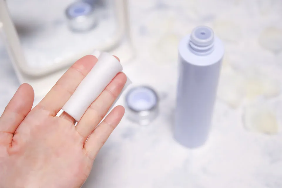 コットンと手で化粧水をつける写真