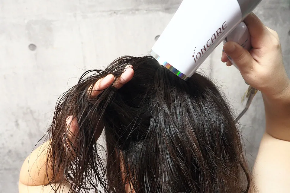 ドライヤーで髪を乾かしている画像