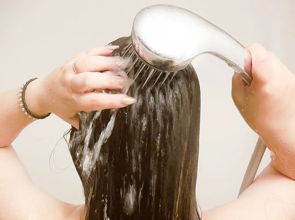 シャワーでシャンプーを流している写真