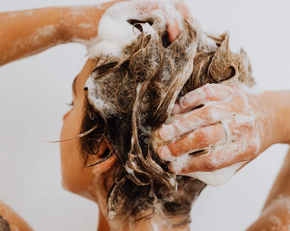 カラーケアシャンプーを使う女性の写真