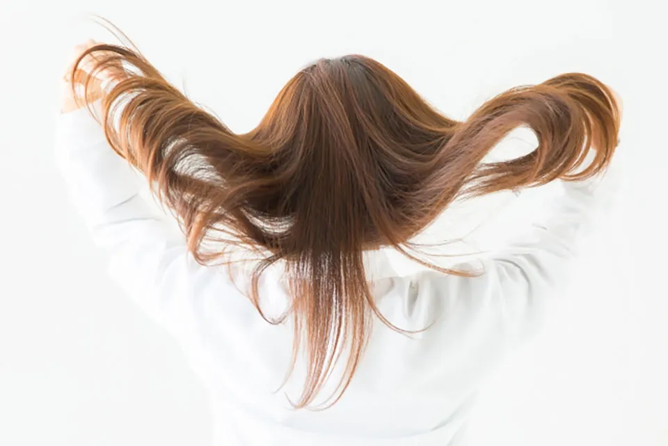 髪をかきあげる女性の写真