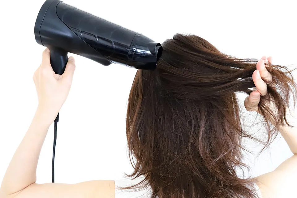 ドライヤーを使っている女性の写真