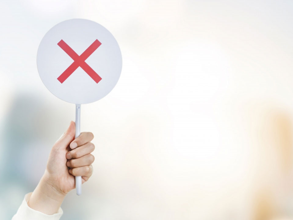 バツマークを掲げる人の画像